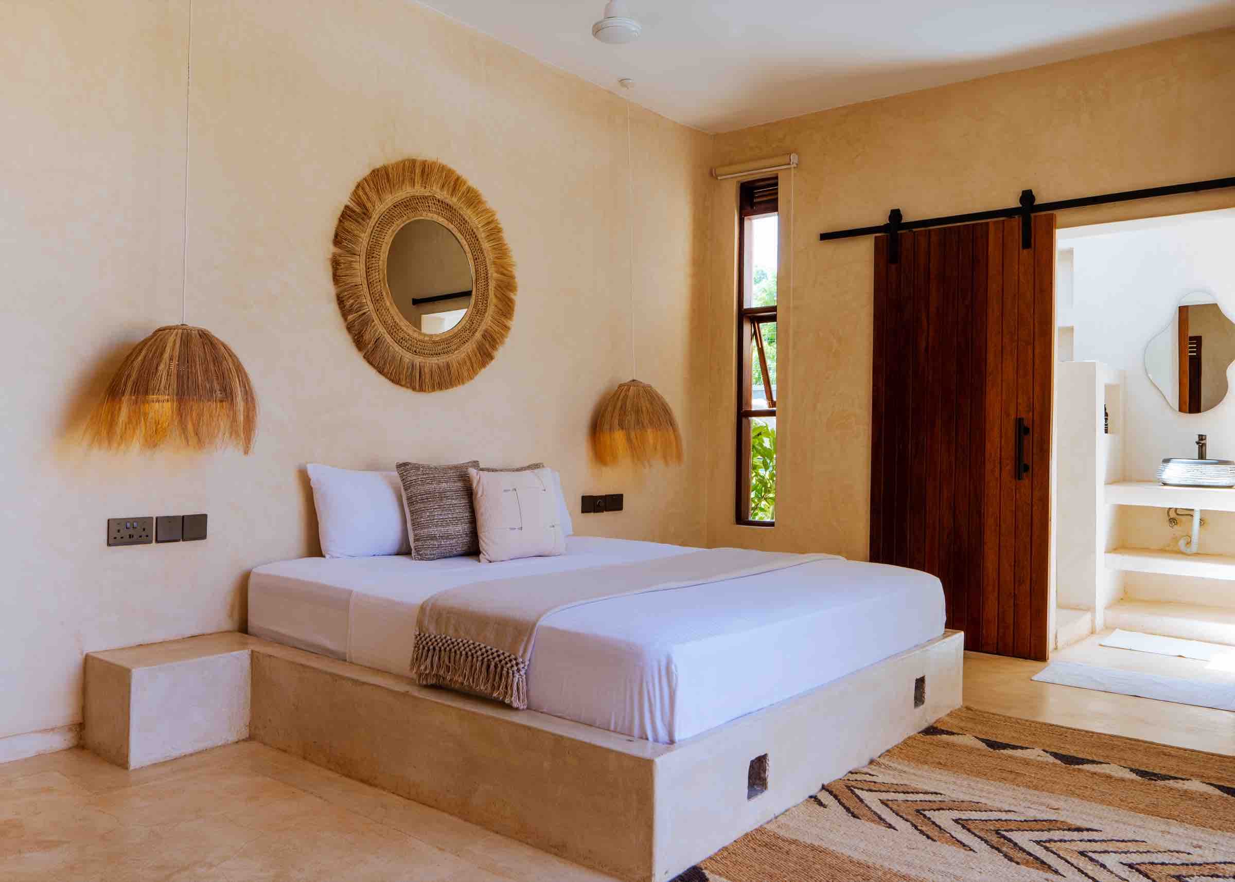 King bed with round rattan mirror and pendant lamps